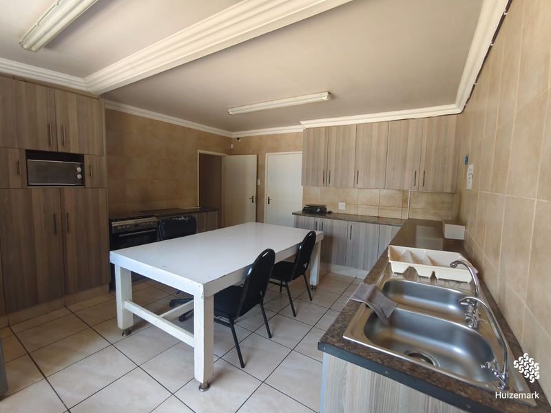 Functional kitchen featuring built-in cabinetry, double stainless steel sink, tiled surfaces, and integrated oven, offering a practical layout for daily meal preparation.