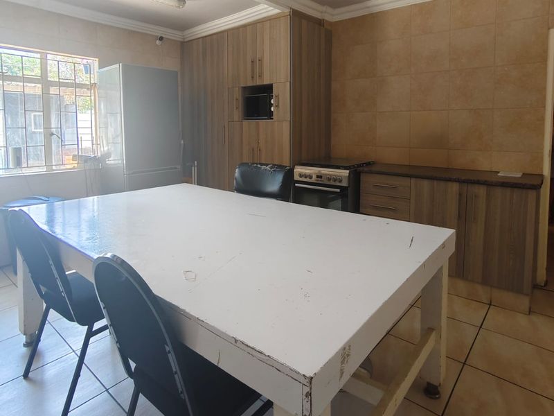 A functional kitchen featuring built-in cabinetry, tiled backsplash, and a freestanding stove, offering a practical layout with potential for cosmetic updates.