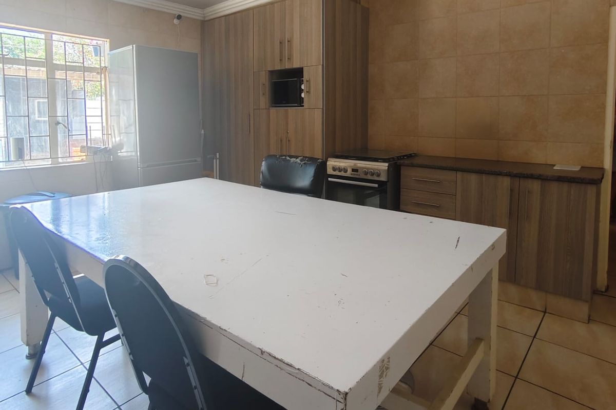 A functional kitchen featuring built-in cabinetry, tiled backsplash, and a freestanding stove, offering a practical layout with potential for cosmetic updates.