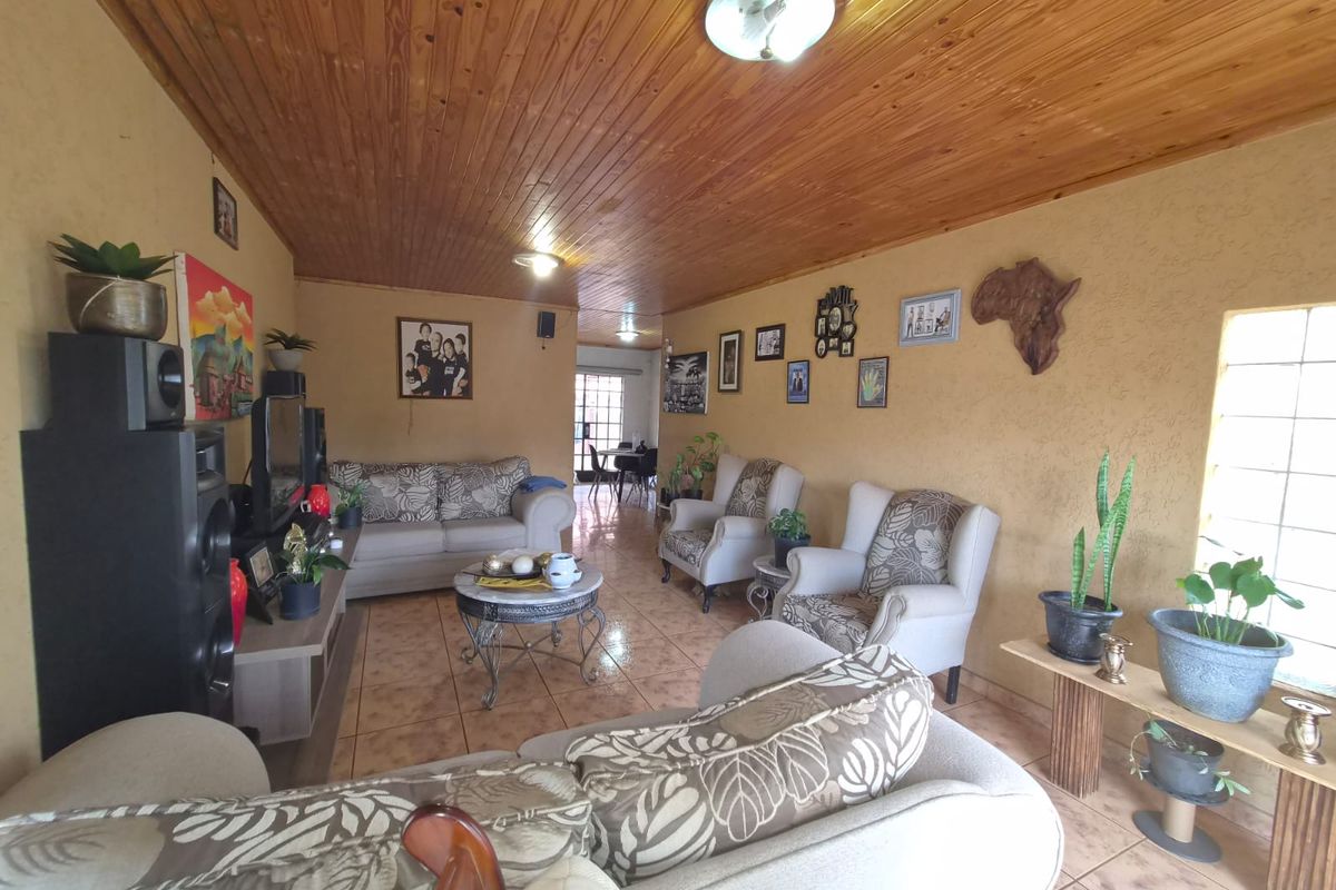 A spacious living room featuring a warm timber tongue and groove ceiling and ceramic floor tiles, offering a comfortable and traditional living environment.