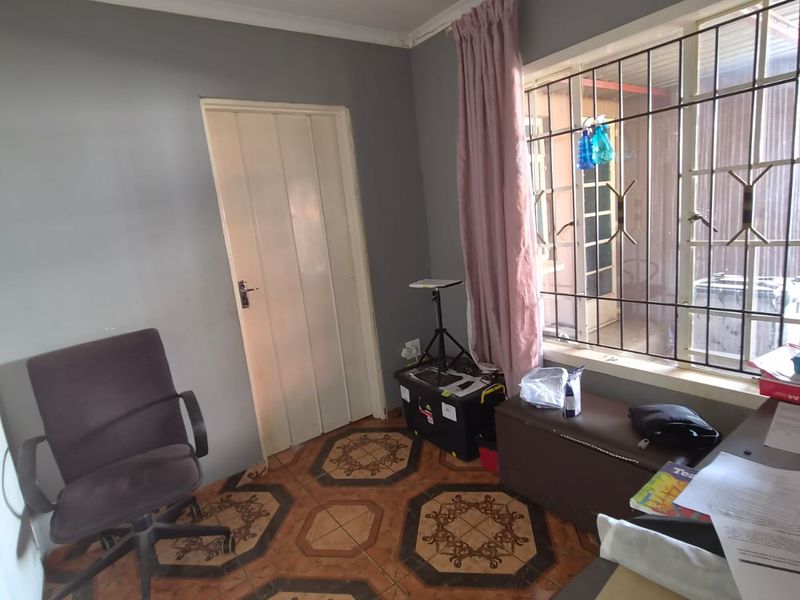 A bedroom featuring tiled flooring, security bars on the window, and neutral wall paint, offering a functional space ready for cosmetic updates.