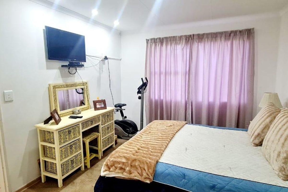 A functional bedroom featuring neutral walls, recessed lighting, and a window with curtain tracks, offering a comfortable and well-lit living space.