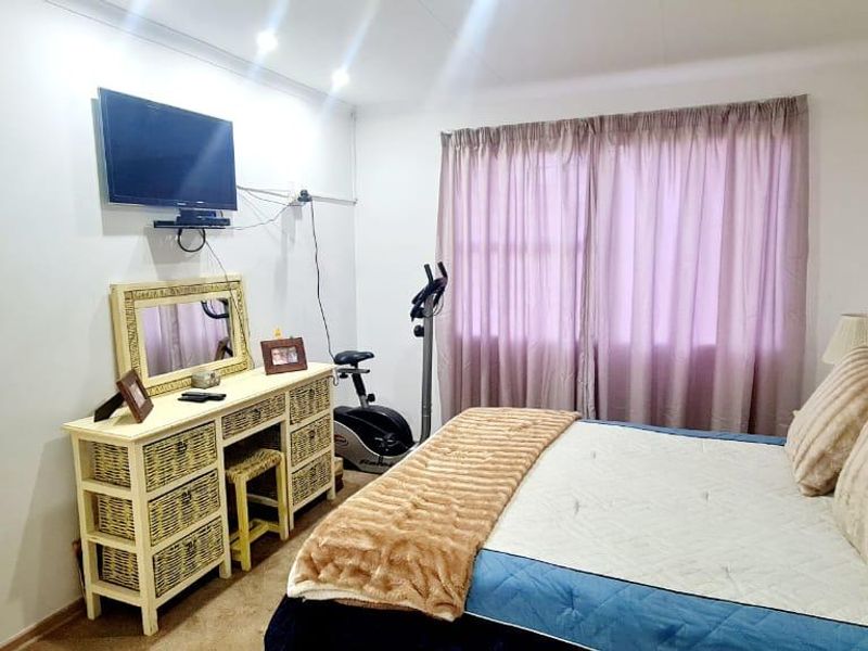 A functional bedroom featuring neutral walls, recessed lighting, and a window with curtain tracks, offering a comfortable and well-lit living space.
