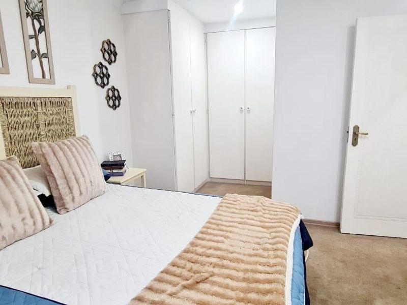 A bedroom featuring neutral walls, carpeted flooring, and built-in cupboards for storage.