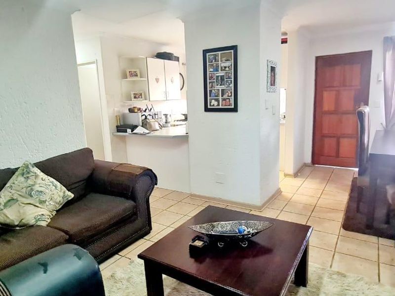 Open-plan living and dining area featuring tiled flooring, coved ceilings, and a functional kitchen with a breakfast counter and direct access to the entrance.