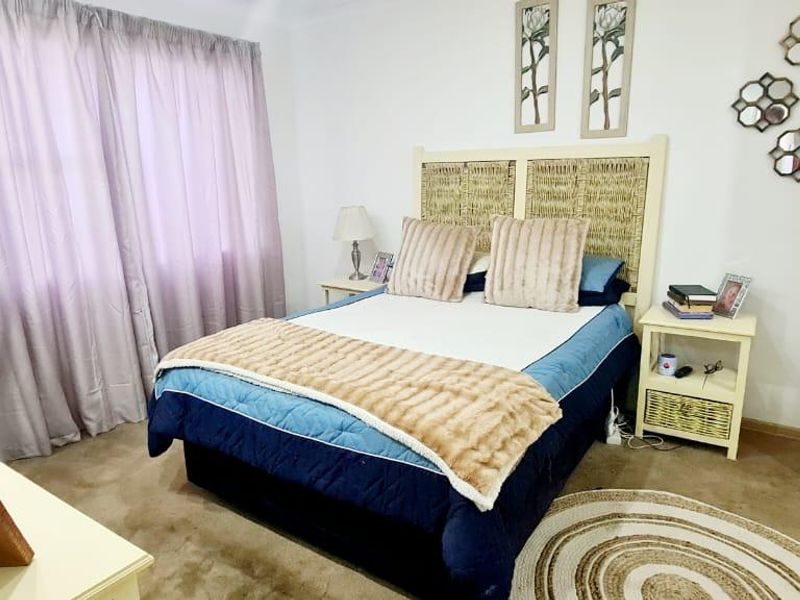 A carpeted bedroom featuring a built-in wardrobe and large window with curtains, providing a functional and comfortable sleeping space.