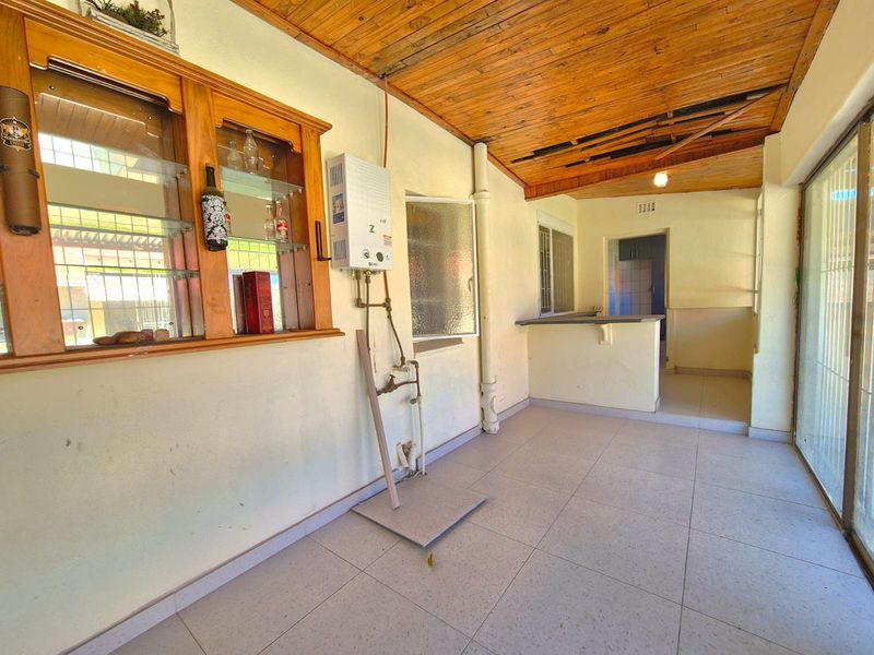 Covered patio area featuring a timber ceiling, tiled flooring, built-in display cabinetry, and a breakfast counter connecting to the interior space.