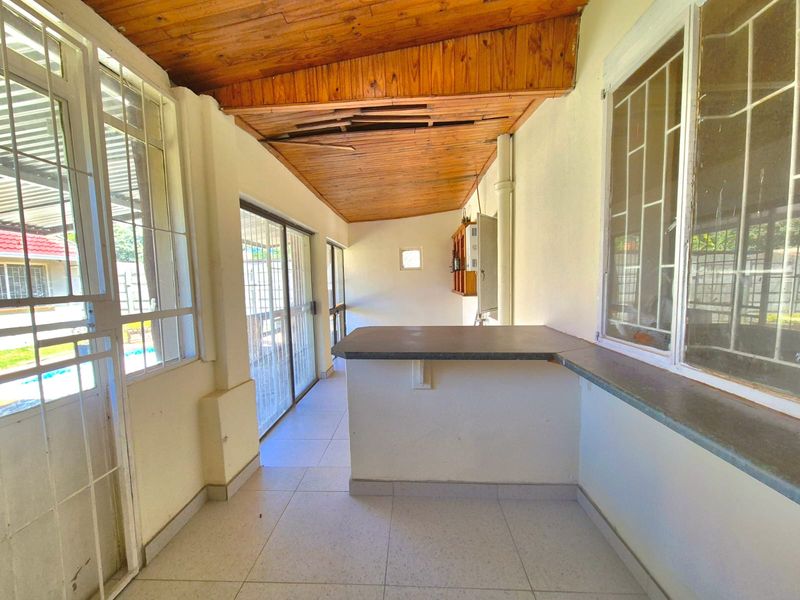 Covered patio area featuring a timber ceiling, tiled flooring, and a built-in counter, offering a functional space for outdoor entertaining.