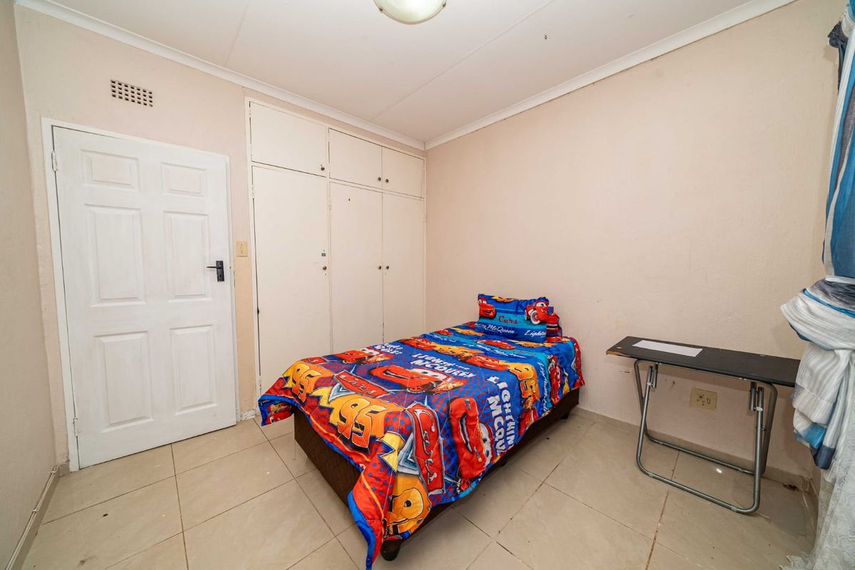A functional bedroom featuring tiled flooring, built-in cupboards, and a ceiling light fixture, offering a practical space for rest or study.