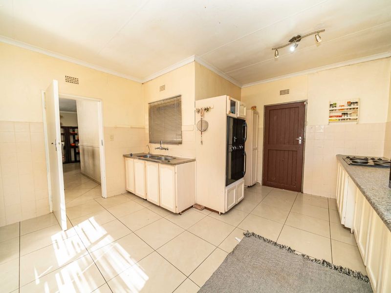 A functional kitchen featuring tiled flooring, built-in cabinetry, a double sink, and integrated oven and hob, offering a practical layout for daily use.