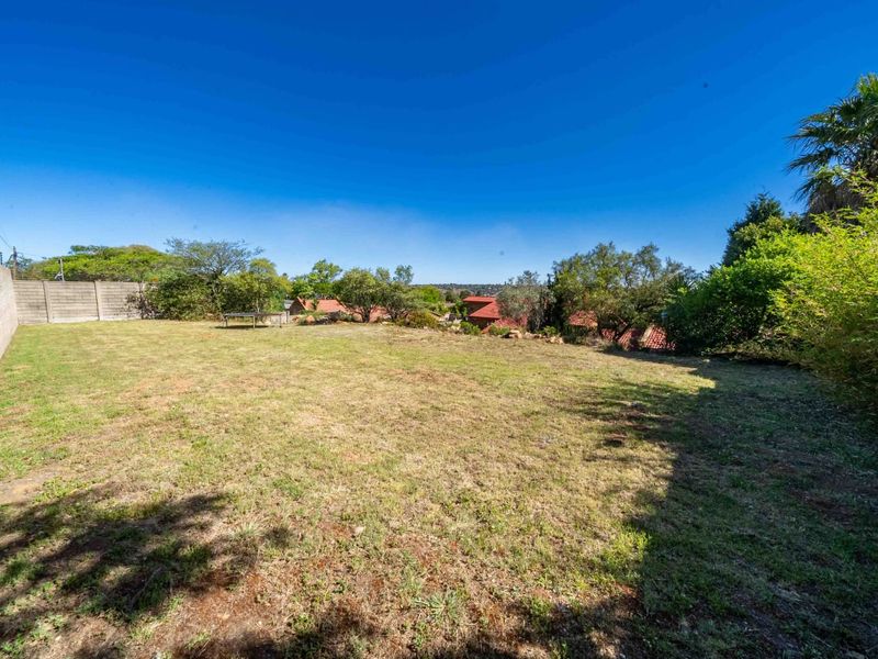 A spacious, open backyard garden featuring a large lawn area enclosed by a perimeter wall, offering potential for landscaping or outdoor development.