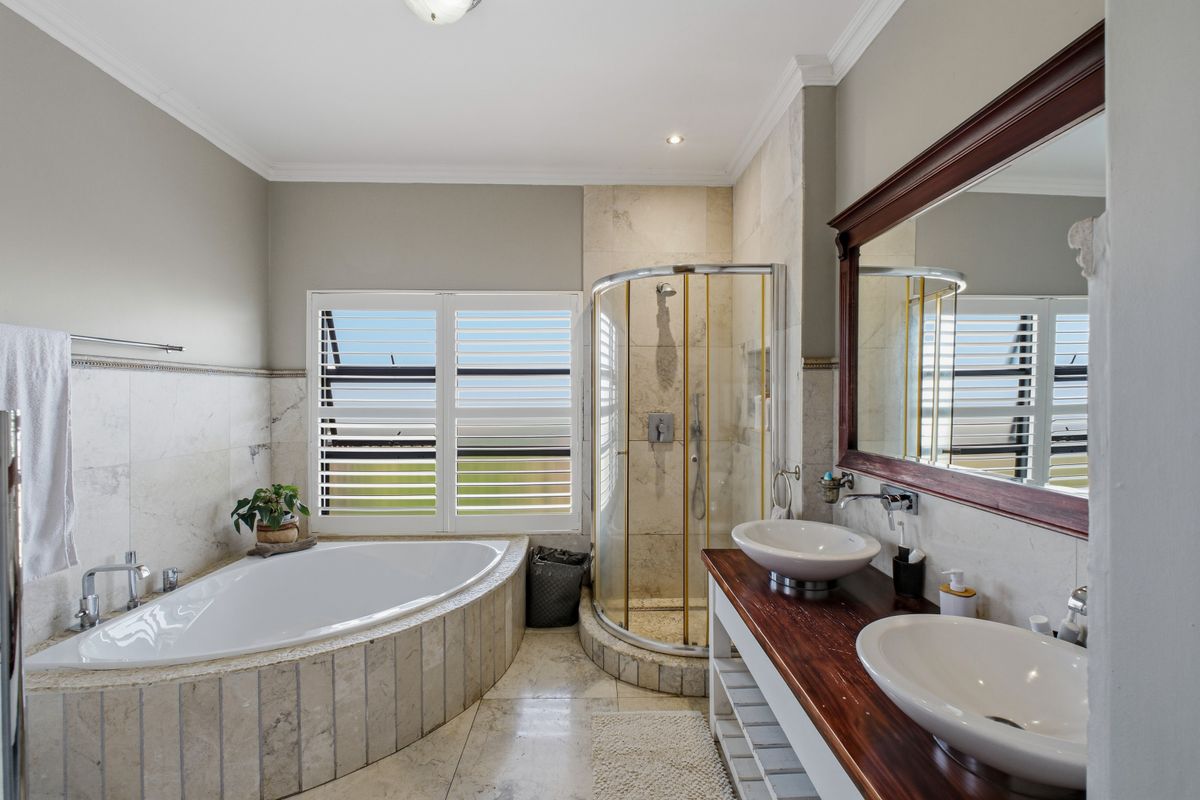 A well-appointed bathroom featuring a corner bathtub, a separate glass-enclosed shower, and a double vanity with vessel sinks and stone finishes.