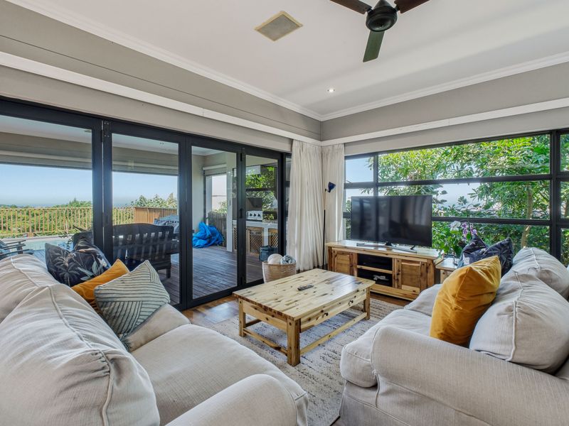 Spacious living room featuring large aluminium framed windows and sliding doors that provide abundant natural light and seamless access to the outdoor deck area.