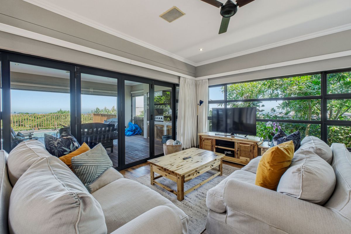 Spacious living room featuring large aluminium framed windows and sliding doors that provide abundant natural light and seamless access to the outdoor deck area.