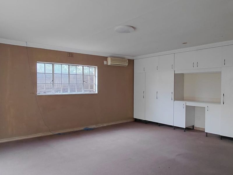 Spacious bedroom featuring extensive built-in cabinetry, wall-mounted air conditioning, and neutral wall finishes, offering a blank canvas for personalization.