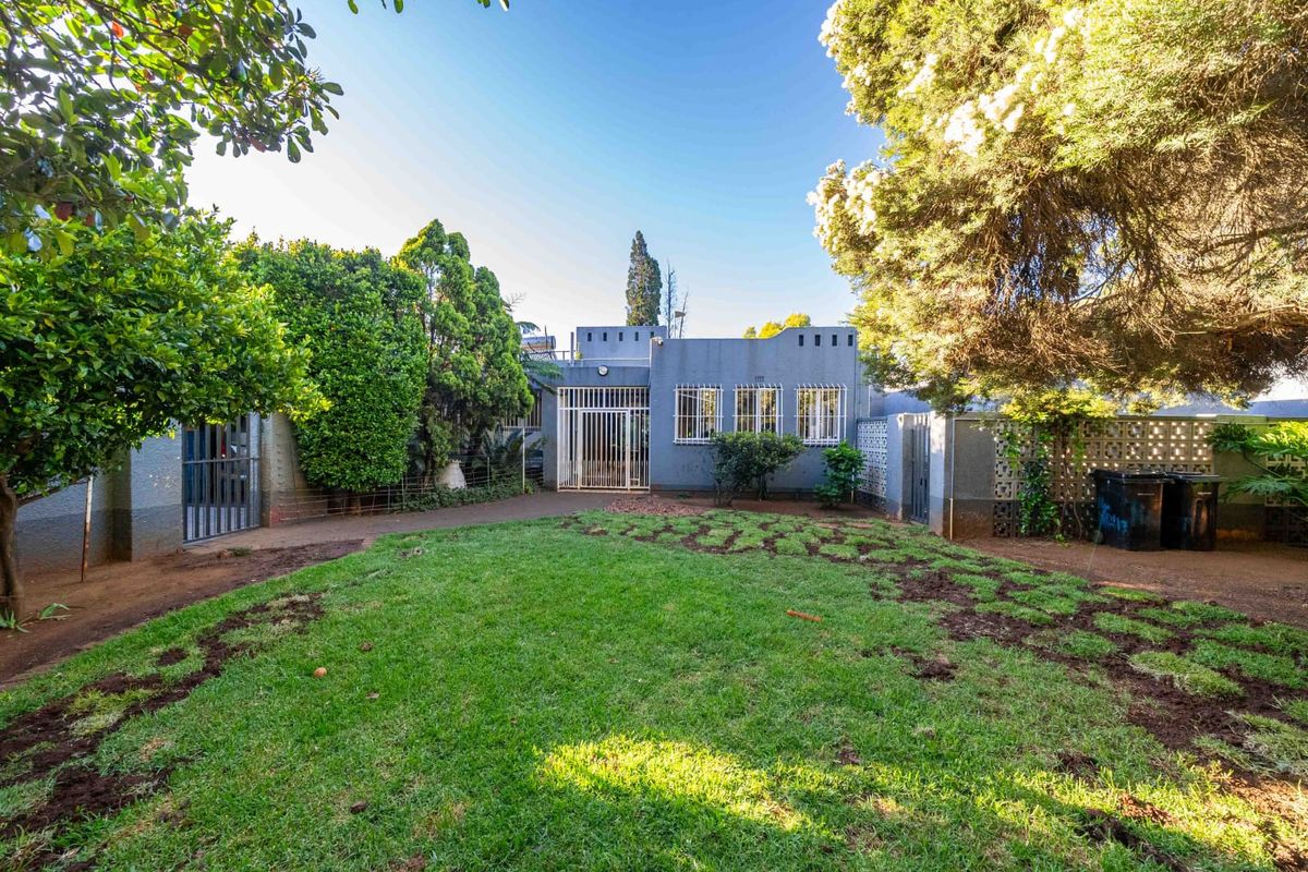 Rear view of the property featuring a private garden, security gates, and established perimeter walling.