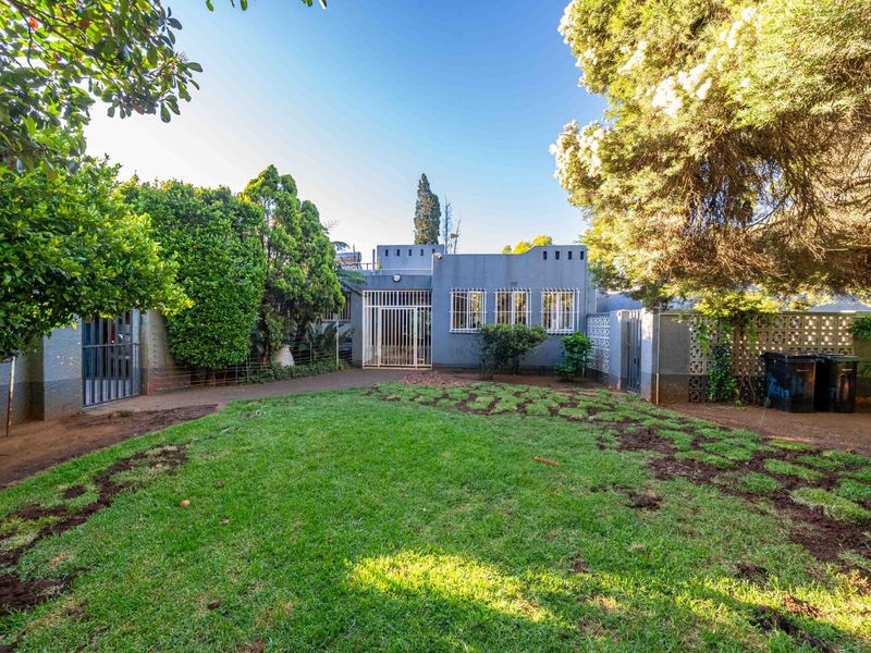 Rear view of the property featuring a private garden, security gates, and established perimeter walling.