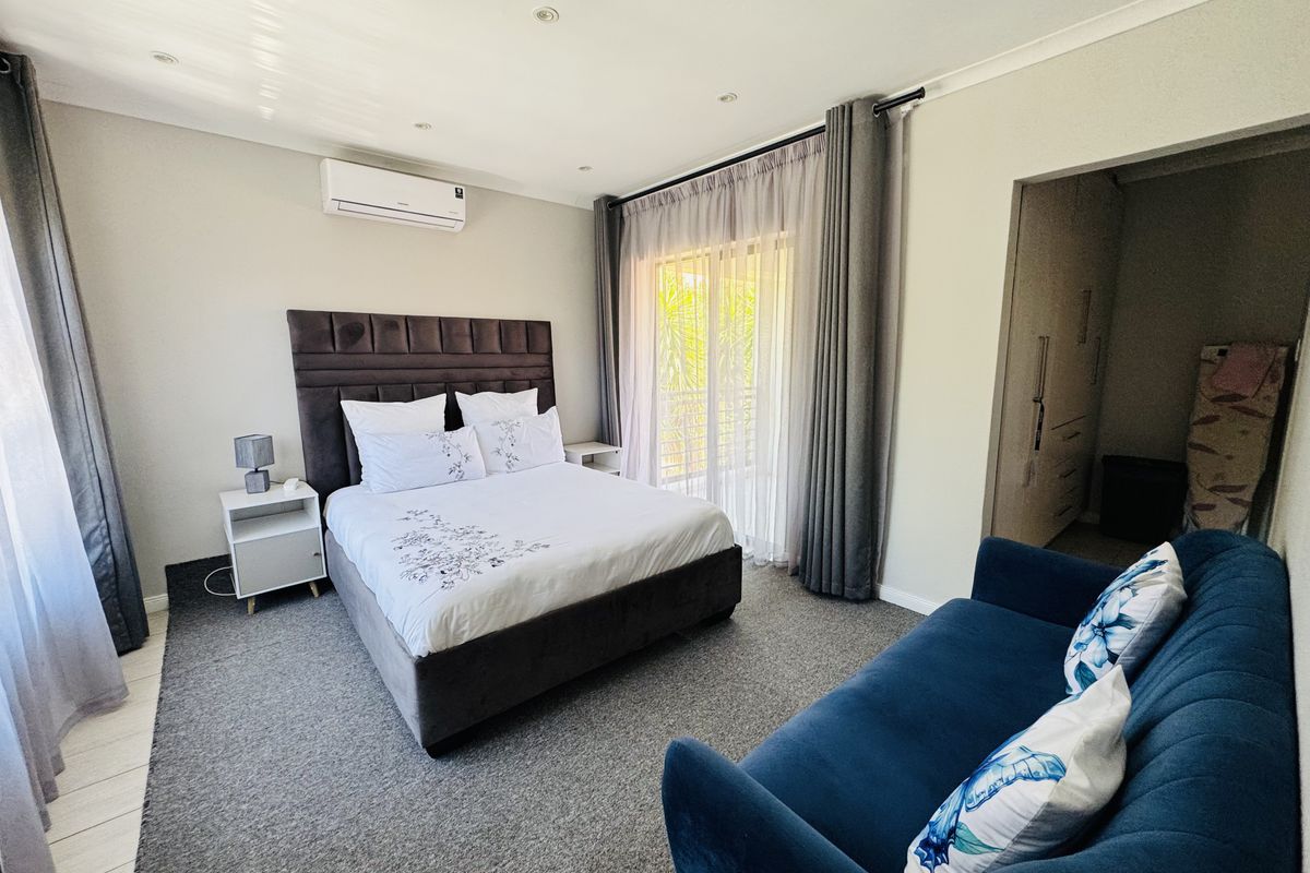 A well-maintained bedroom featuring carpet flooring, recessed lighting, an air conditioning unit, and a sliding glass door leading to an outdoor area.
