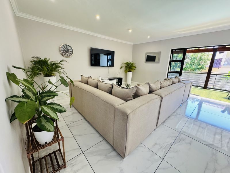 Spacious living room featuring modern marble-look porcelain floor tiles, recessed downlighting, and large sliding glass doors leading to an outdoor area.