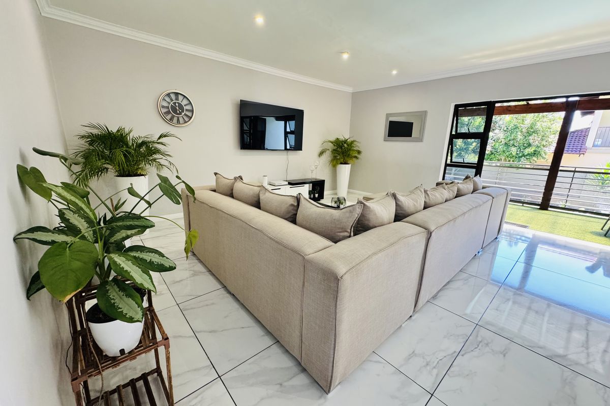 Spacious living room featuring modern marble-look porcelain floor tiles, recessed downlighting, and large sliding glass doors leading to an outdoor area.