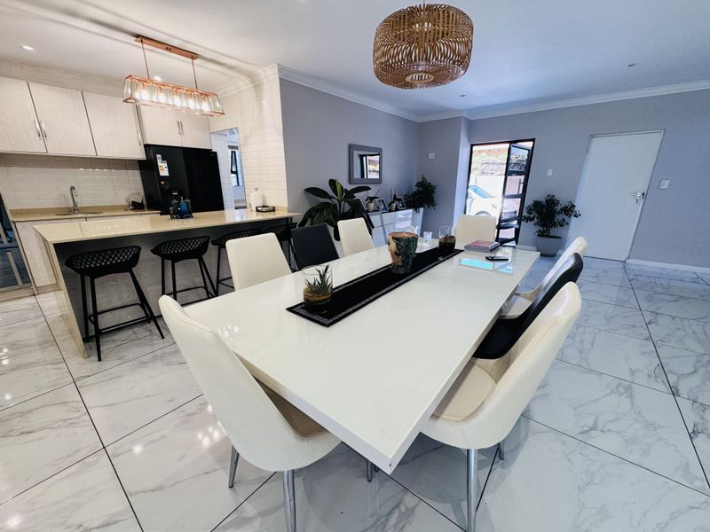 Modern open-plan living and dining area featuring a sleek kitchen with quartz countertops, tiled flooring, and contemporary lighting fixtures.