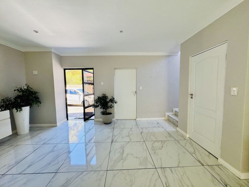 A bright and spacious entrance hall featuring modern marble-look floor tiles, clean neutral walls, and direct access to the exterior.