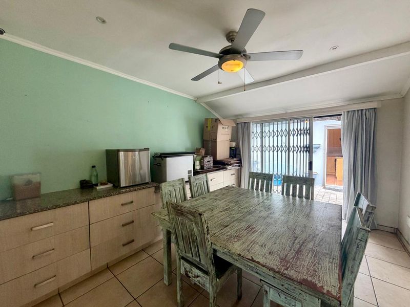 Dining area featuring built-in cabinetry with granite countertops, tiled flooring, a ceiling fan, and sliding door access to the exterior.