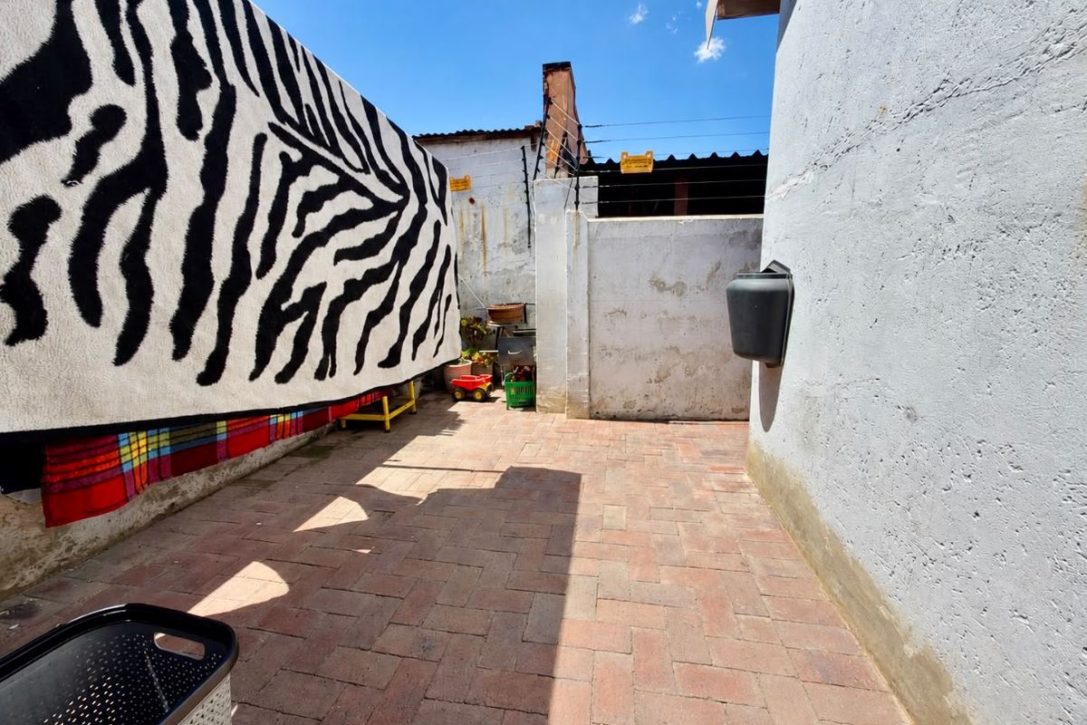 A rear exterior courtyard area featuring brick paving, perimeter walls with electric fencing, and a wall-mounted mailbox.