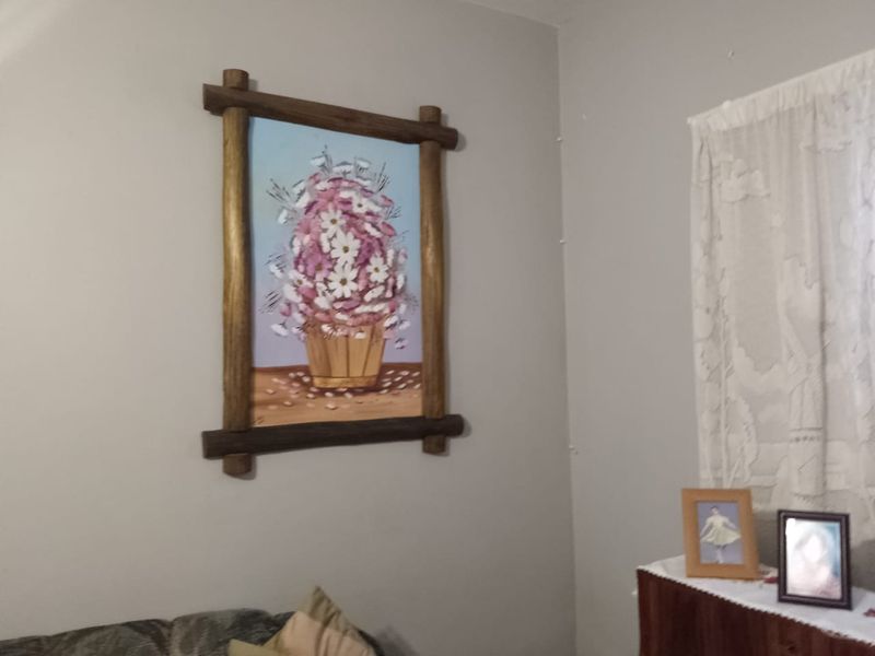 A close-up view of a wall featuring a framed floral artwork and a sheer curtain.