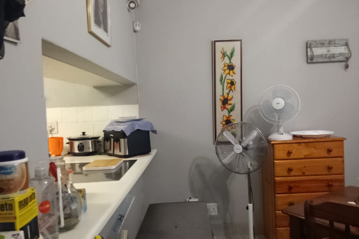 A compact kitchen area featuring a built-in countertop with a tiled backsplash and integrated electrical outlets.