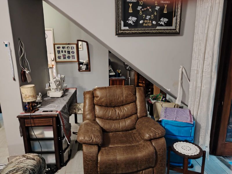 A living area featuring a sloped ceiling and tiled flooring, currently utilized as a multi-purpose space.