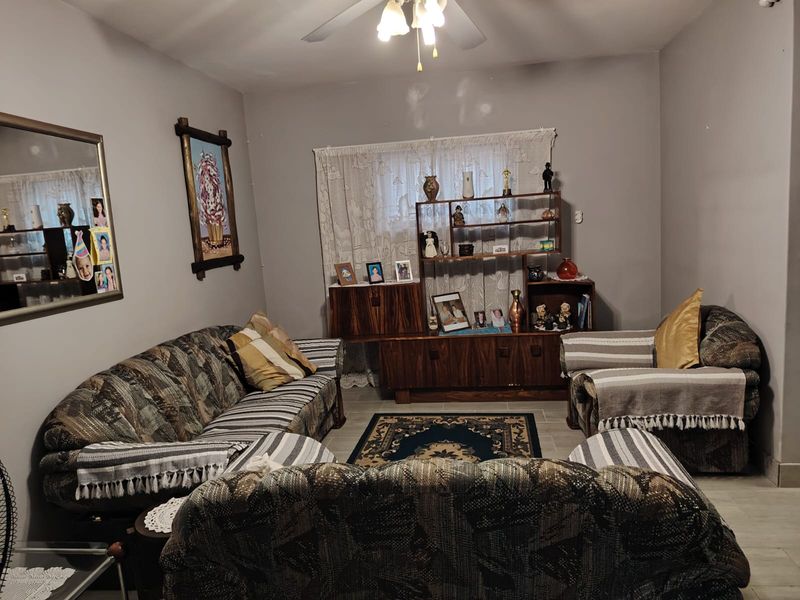 A living room featuring tiled flooring and a ceiling fan, with neutral wall tones ready for a modern update.