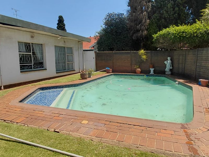 Outdoor pool area featuring a swimming pool with brick coping, enclosed by a brick boundary wall and adjacent to the rear of the house.