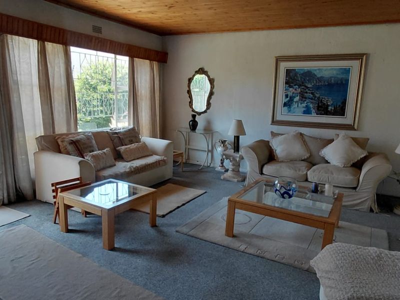 Spacious living room featuring timber ceilings, carpeted flooring, and large sliding glass doors providing direct access to the outdoor patio area.
