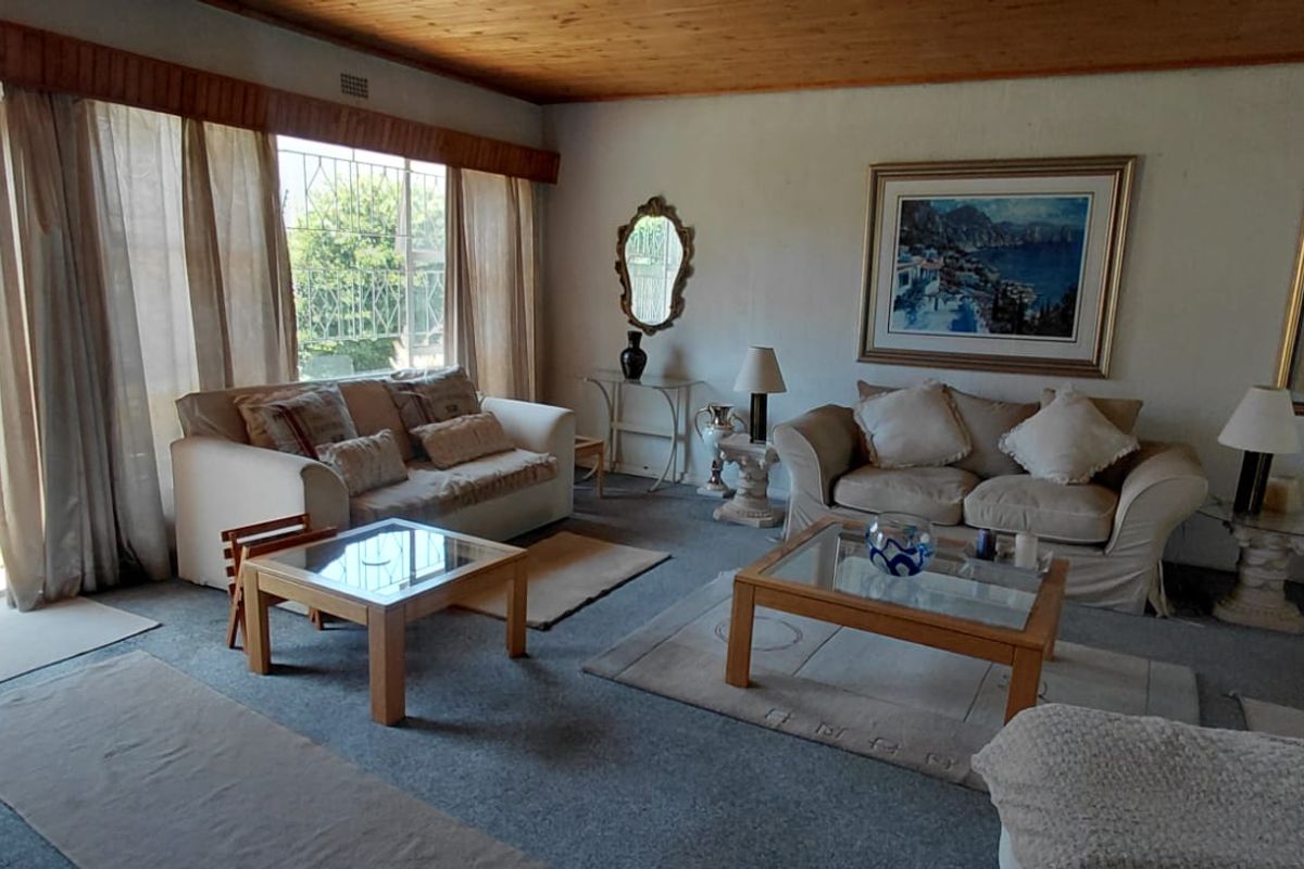Spacious living room featuring timber ceilings, carpeted flooring, and large sliding glass doors providing direct access to the outdoor patio area.