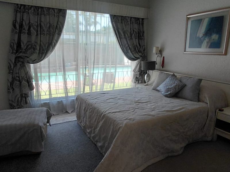 A bedroom featuring built-in cupboards and a sliding door providing direct access to the pool area.