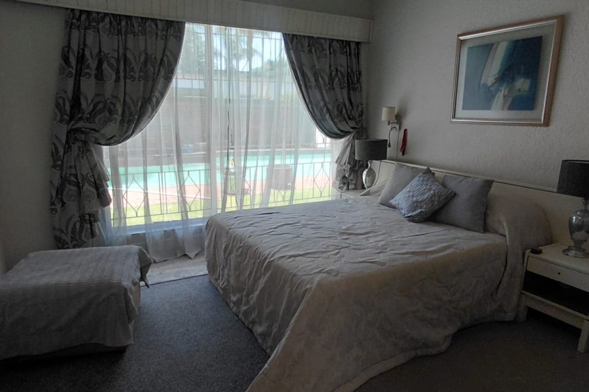 A bedroom featuring built-in cupboards and a sliding door providing direct access to the pool area.