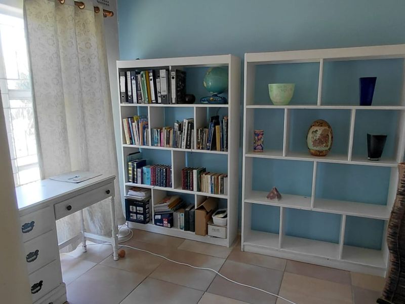 A functional home office space featuring tiled flooring and natural light from a side window, suitable for a dedicated workspace.