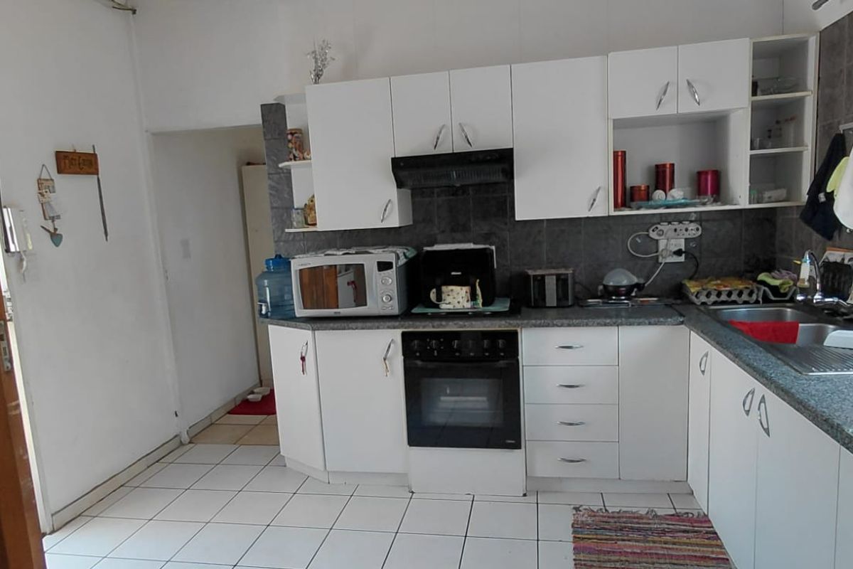 A functional kitchen featuring white cabinetry, a built-in oven with extractor fan, tiled backsplash, and tiled flooring.