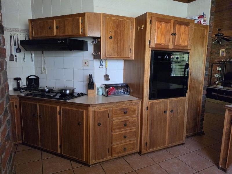 A functional kitchen featuring traditional wooden cabinetry, a built-in oven, a hob with an extractor fan, and tiled finishes throughout.