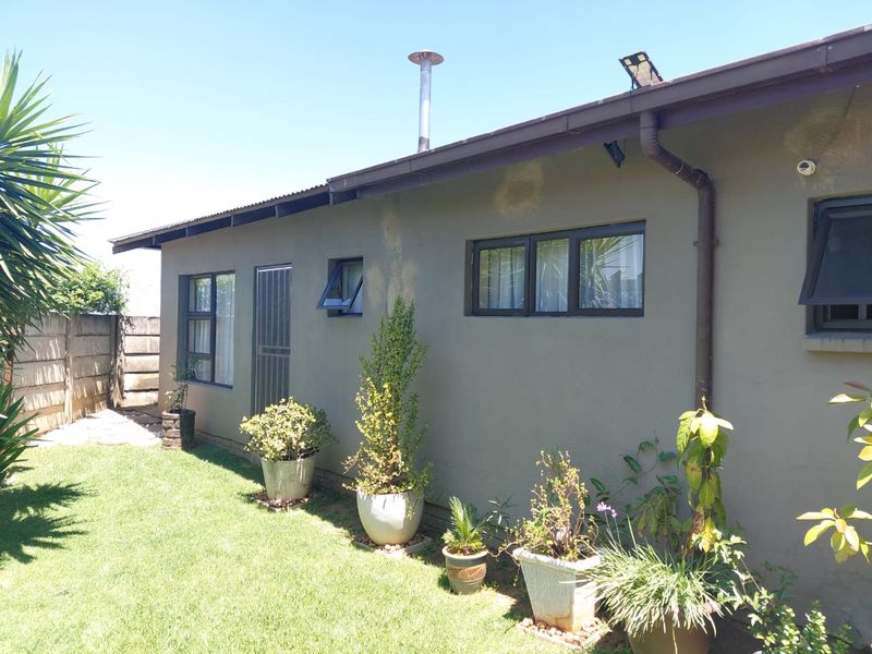 Rear exterior view of the house featuring a corrugated metal roof, gutter system, and aluminium window frames with visible wall staining.