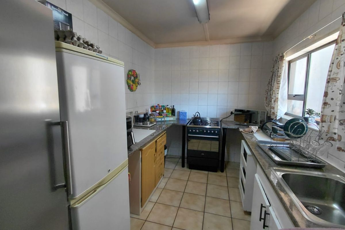 A functional kitchen featuring tiled splashbacks, built-in cabinetry, and a freestanding stove, offering a practical layout with potential for modern updates.