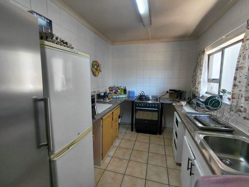 A functional kitchen featuring tiled splashbacks, built-in cabinetry, and a freestanding stove, offering a practical layout with potential for modern updates.