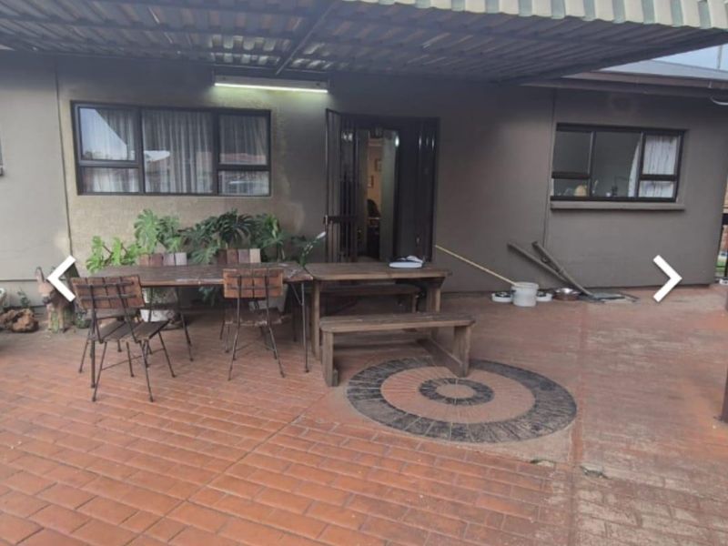 A covered outdoor patio area featuring brick paving and direct access to the home through a security gate.