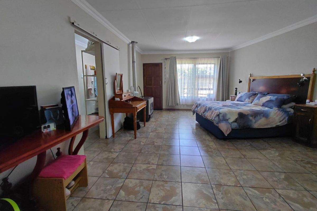 Spacious bedroom featuring tiled flooring, a wood-burning stove, and direct access to an adjoining room via a sliding door.