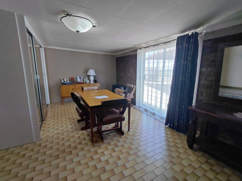 Dining room featuring tiled flooring, an exposed brick feature wall, and a sliding glass door providing access to the outdoor area.