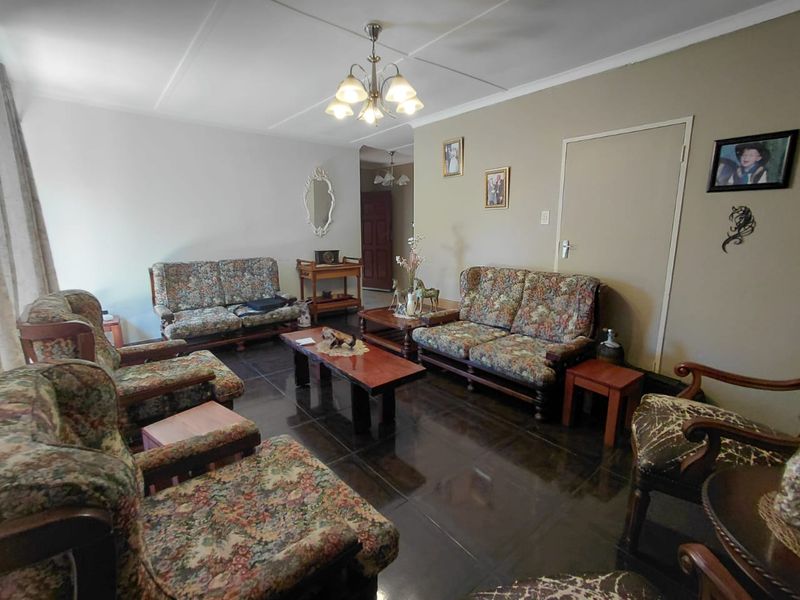 A spacious living room featuring dark tiled flooring and a central ceiling light fixture, offering a functional layout for family relaxation.