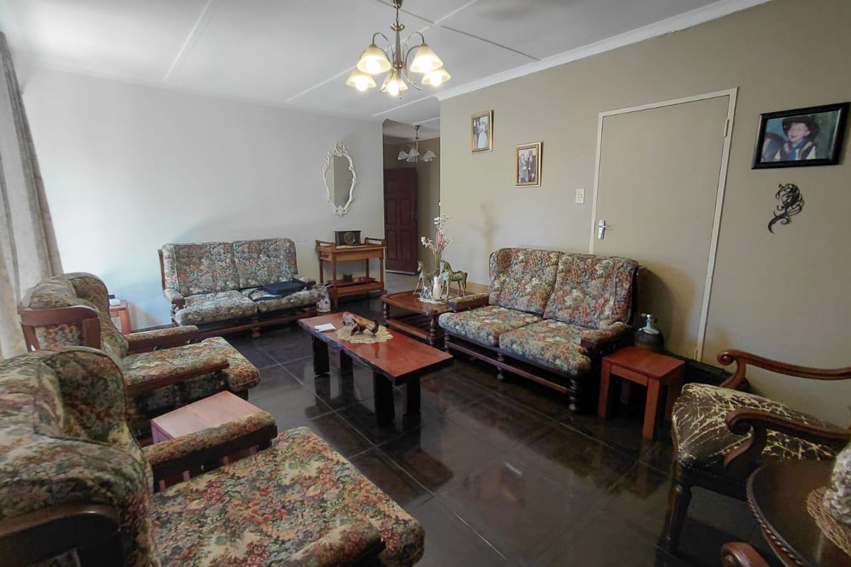 A spacious living room featuring dark tiled flooring and a central ceiling light fixture, offering a functional layout for family relaxation.