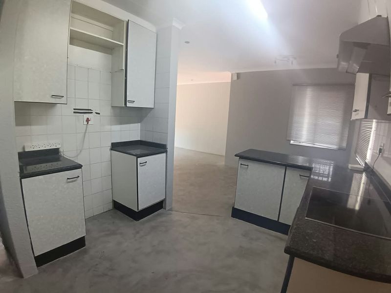 A functional, empty kitchen featuring built-in cabinetry, dark countertops, and a tiled backsplash, offering a clean slate for modern updates.