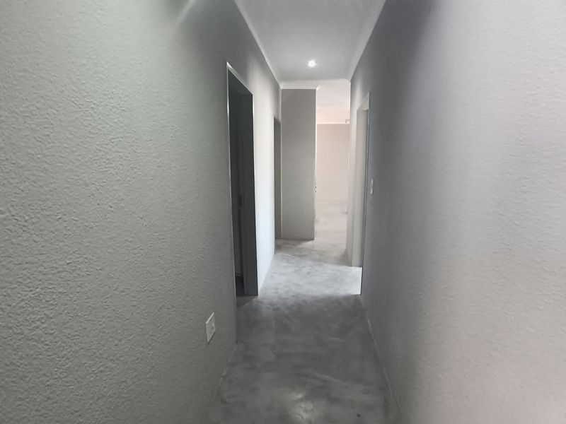 A clean, minimalist hallway featuring polished concrete flooring and recessed downlighting, providing a neutral transition space between rooms.
